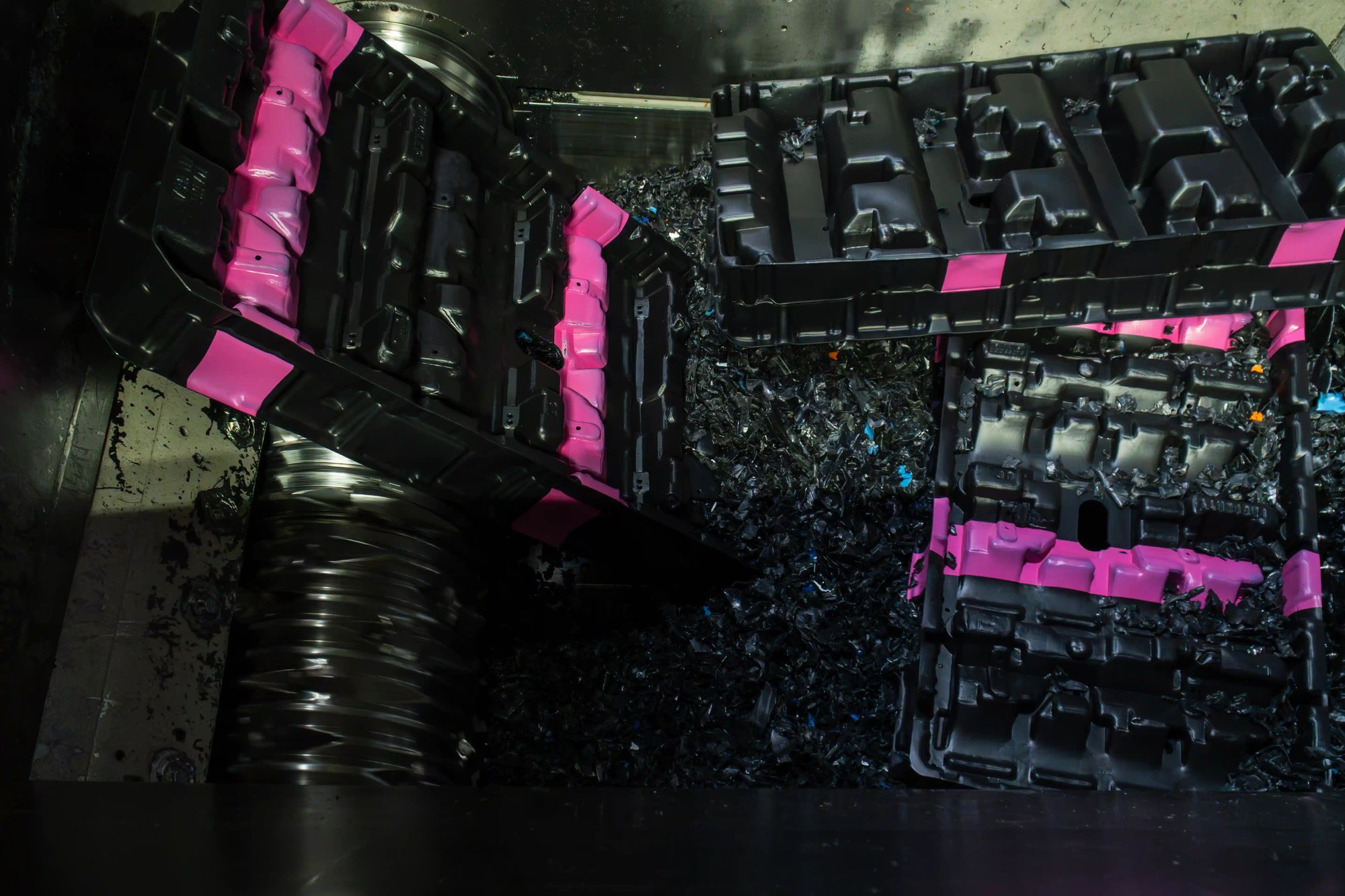 Plastic dunnage trays entering dual-shaft shredder during size reduction at recycling plant. Plastic dunnage trays entering dual-shaft shredder during size reduction at recycling plant.