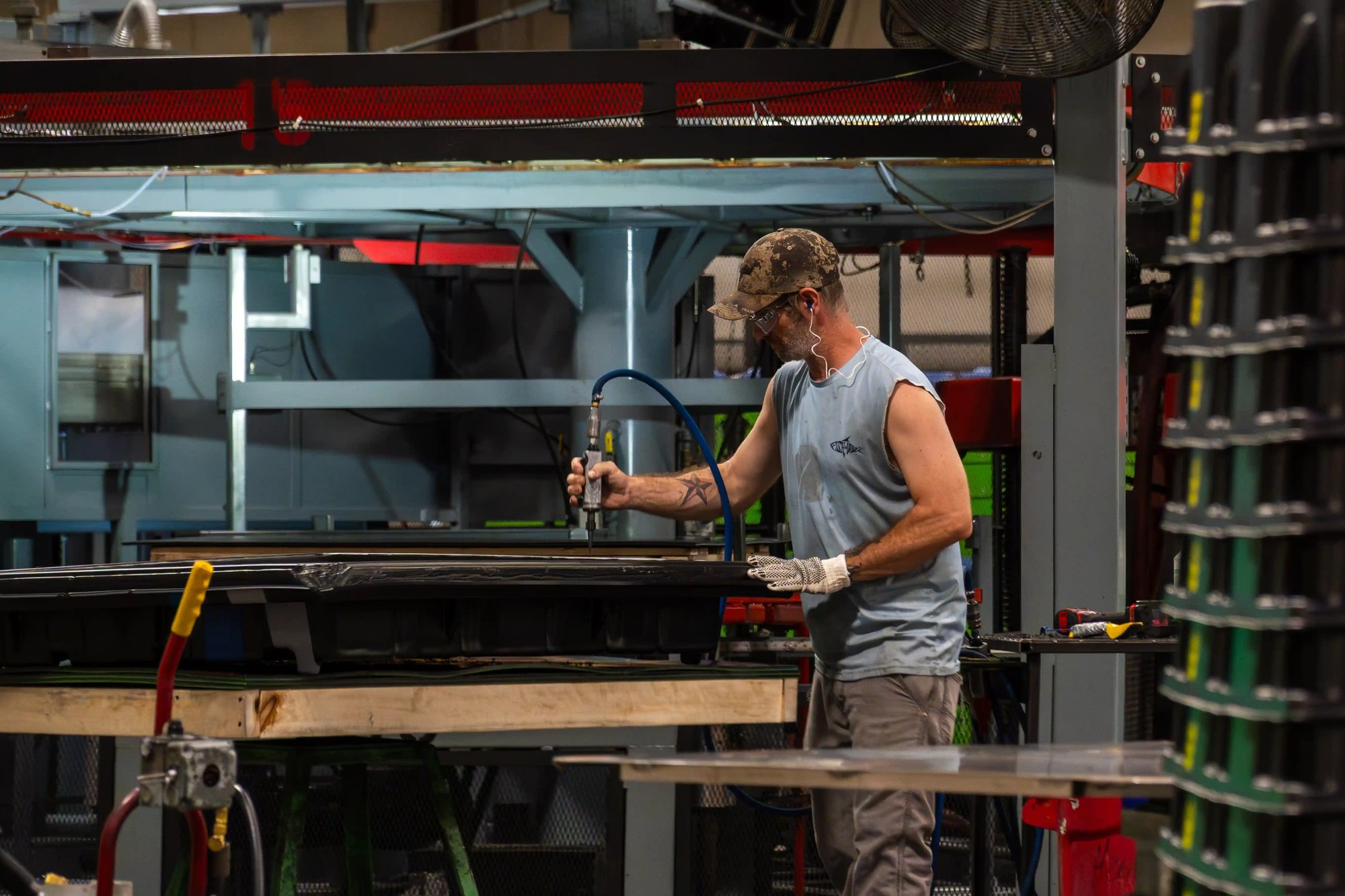 Manufacturing technician prepping plastic part with air tool on production line, PPE in use. Manufacturing technician prepping plastic part with air tool on production line, PPE in use.