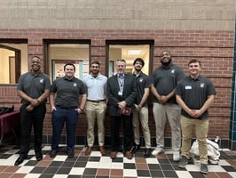 George Aultman and John Tatton stand with CMU engineering students at the Senior Design Expo in front of their project display.